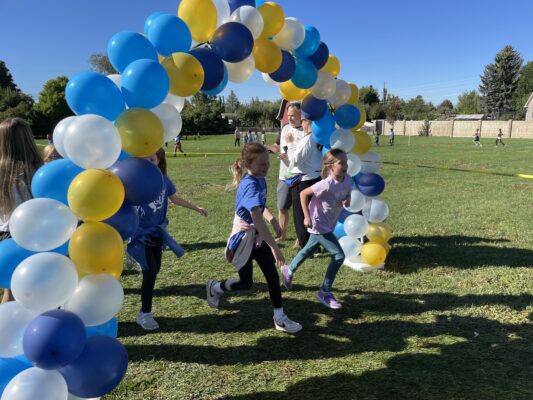Students running under the balloon arch at the Fund Run